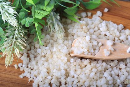 Epsom salt sitting on a wooden table alongside a fake plant