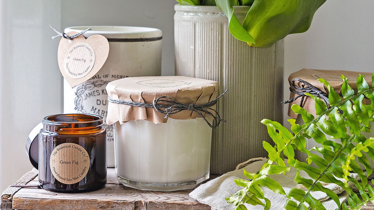 Candles and jars on a wooden shelf beside a vase of tulips