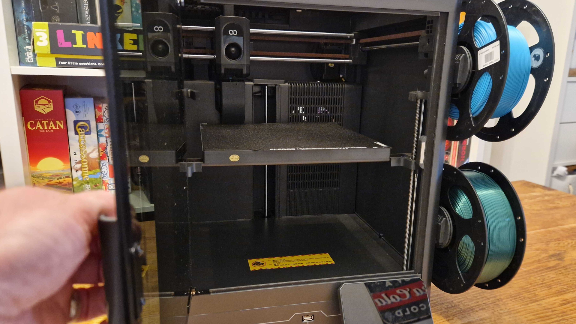 A hand opens the front door of the Elegoo Centauri Carbon 2 Combo