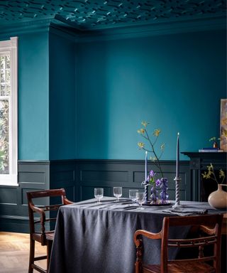 blue-green dining room with grey paneling and grey tablecloth