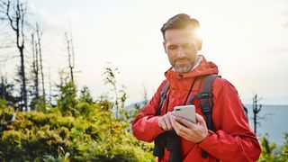 man using a cell phone to calculate his average hiking speed