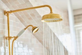 A gold brass shower head running with water 