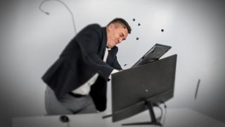  man in a suit gets angry and smashes the keyboard on the monitor