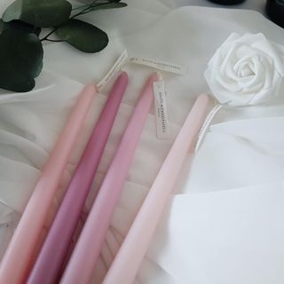 four taper candles in different shades of pink