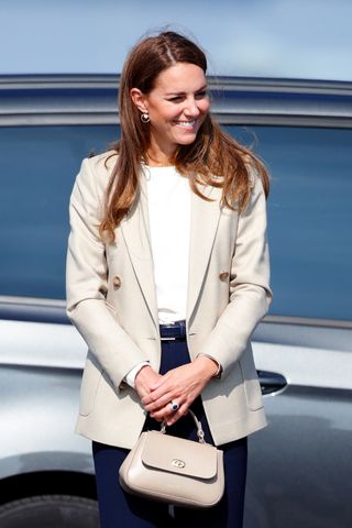 Kate Middleton wears a cream blazer, a white blouse and navy trousers as she arrives to meet those who supported the UK's evacuation of civilians from Afghanistan at RAF Brize Norton on September 15, 2021 in Brize Norton, England.