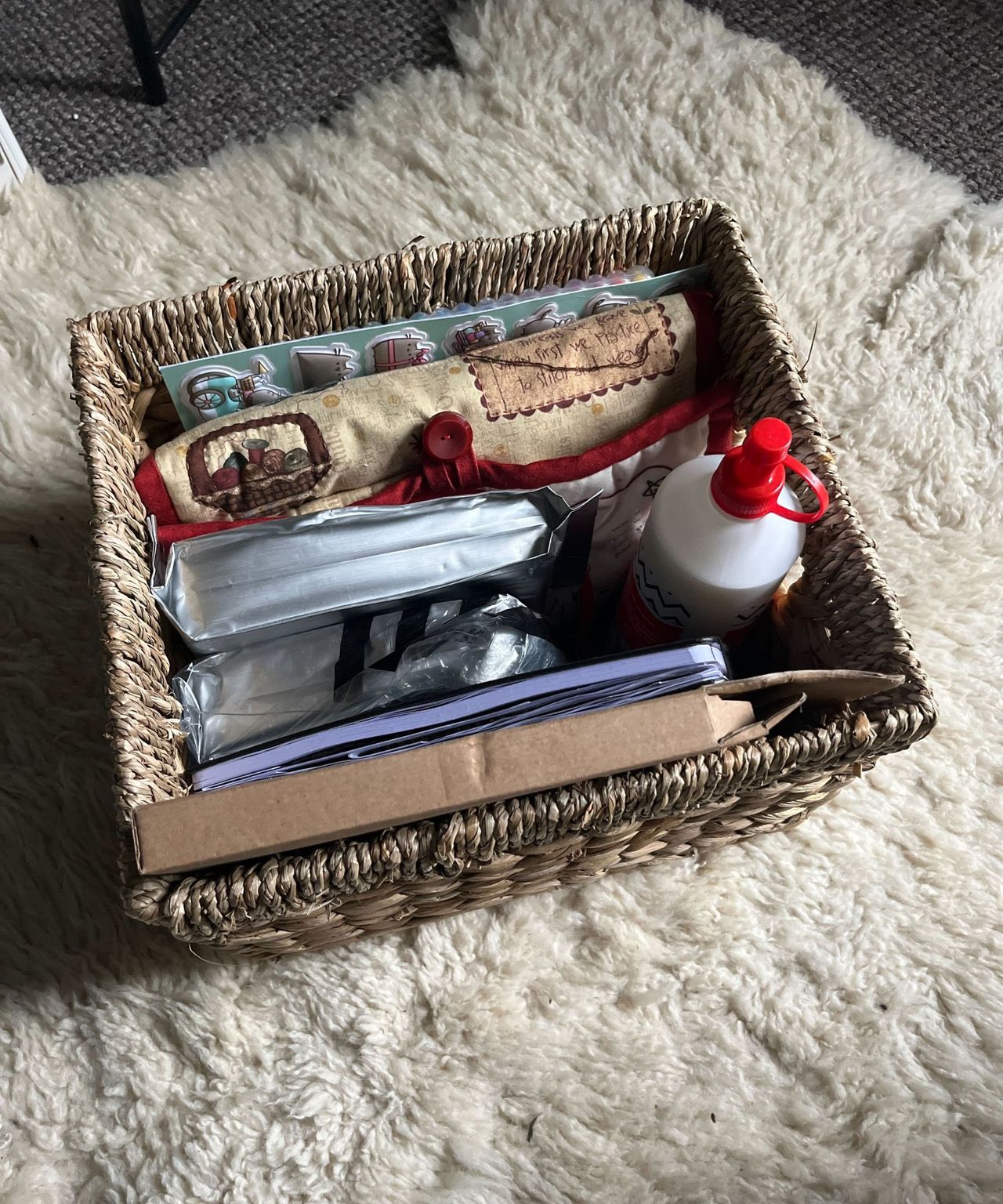 A woven wicker basket full of craft supplies on a sheepskin rug