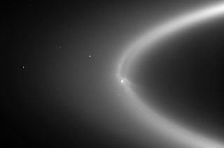 Saturn's moon Enceladus (center right) blasts material into the planet's E ring.