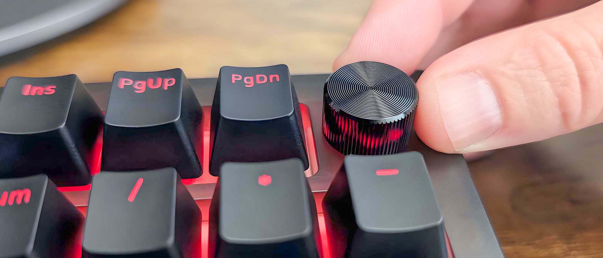 A forefinger and thumb rotating the volume dial on the iBuyPower MK9 Pro RGB Mechanical Keyboard.