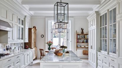 All white kitchen with kitchen island along the centre and metal frame rectangular lantern ceiling lights