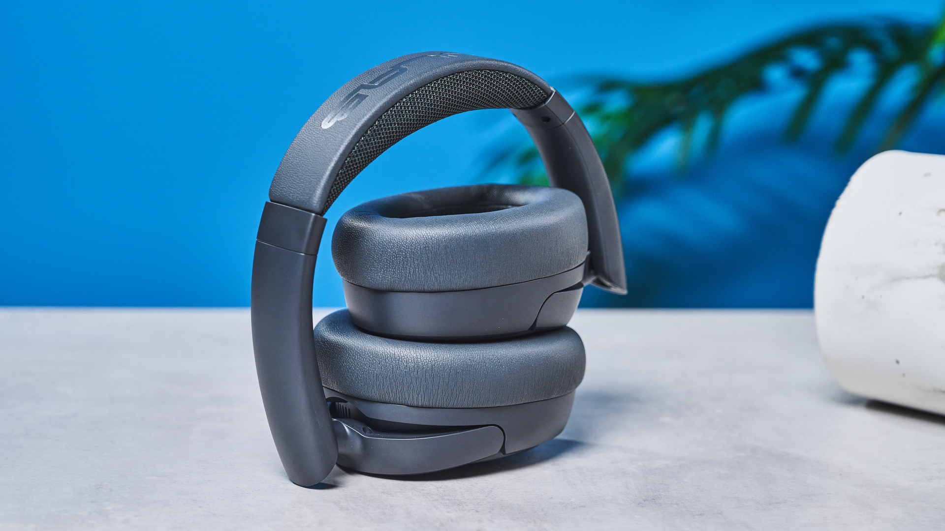 the jlab jbuds lux anc headphones in black photographed against a blue background