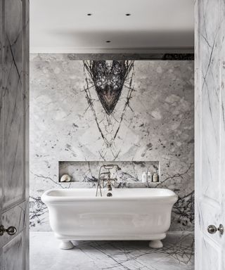 An example of bathroom lighting ideas showing a marble bathroom with a freestanding bath and ceiling spotlights