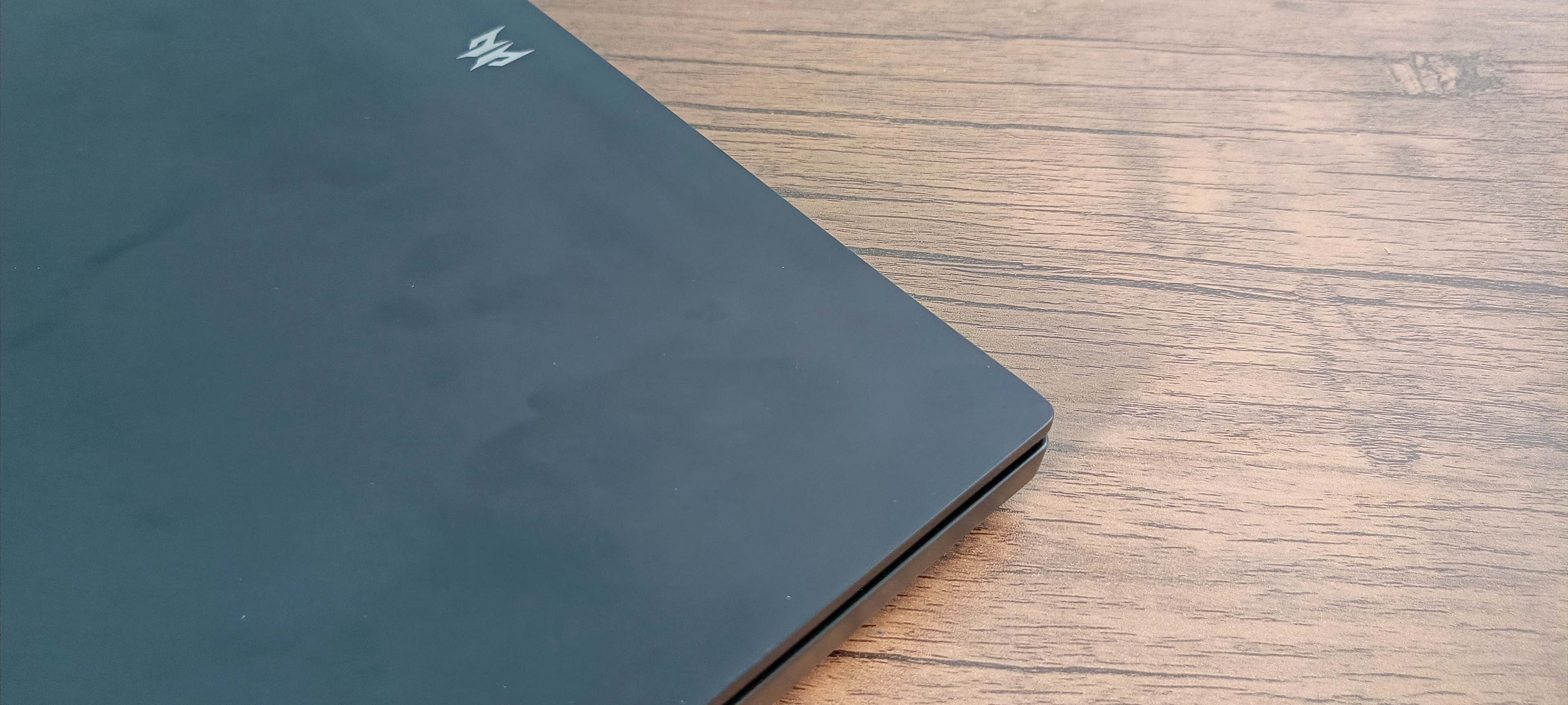 An Abyss Black Acer Predator Helios 16 gaming laptop sitting on a brown wooden desk
