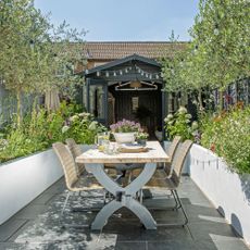 Black shed with white flowerbeds and table