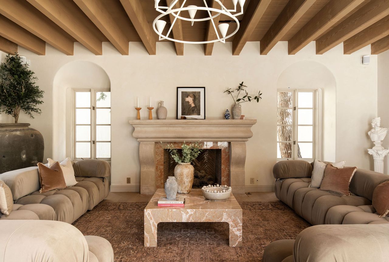 A living room with rounded sofas in taupe and a marble coffee table