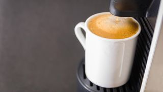 How to use a pod coffee machine: Machine brewing coffee into cup