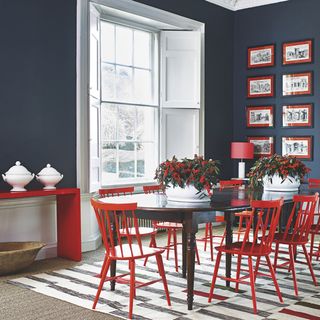 dining room with dining table with talia red dining chairs and navy walls