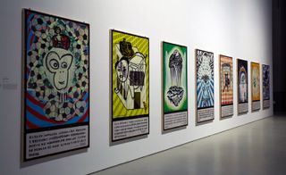 Eight posters displayed on a wall featuring individual character drawings.