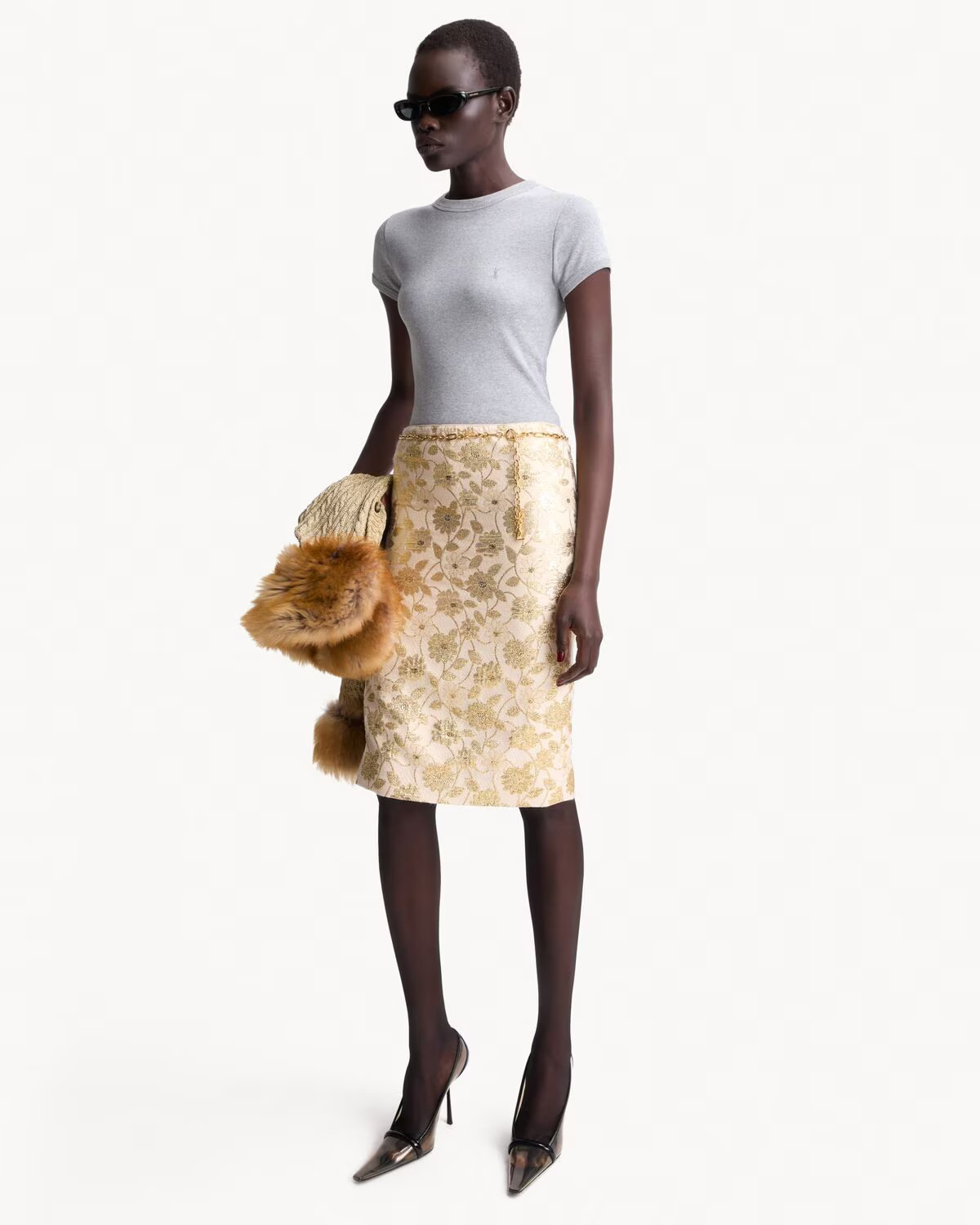 An image of a model wearing a cream yellow brocade skirt and grey T-shirt and black heels