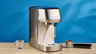 the casabrews 3700 essential espresso machine photographed against a blue background in stainless steel