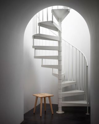 Wooden stool by spiral stairs at Studio Seitz Williamsburg showroom.