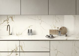 A kitchen countertop with white gold Calcutta marble surfaces and cabinet doors