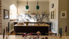 a large london kitchen designed with floral wall to wall wallpaper with a statement marble countertop and backsplash