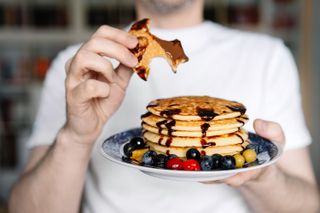 Man holding plate of pancakes after a pancake flipping contest, one of the things to do with kids