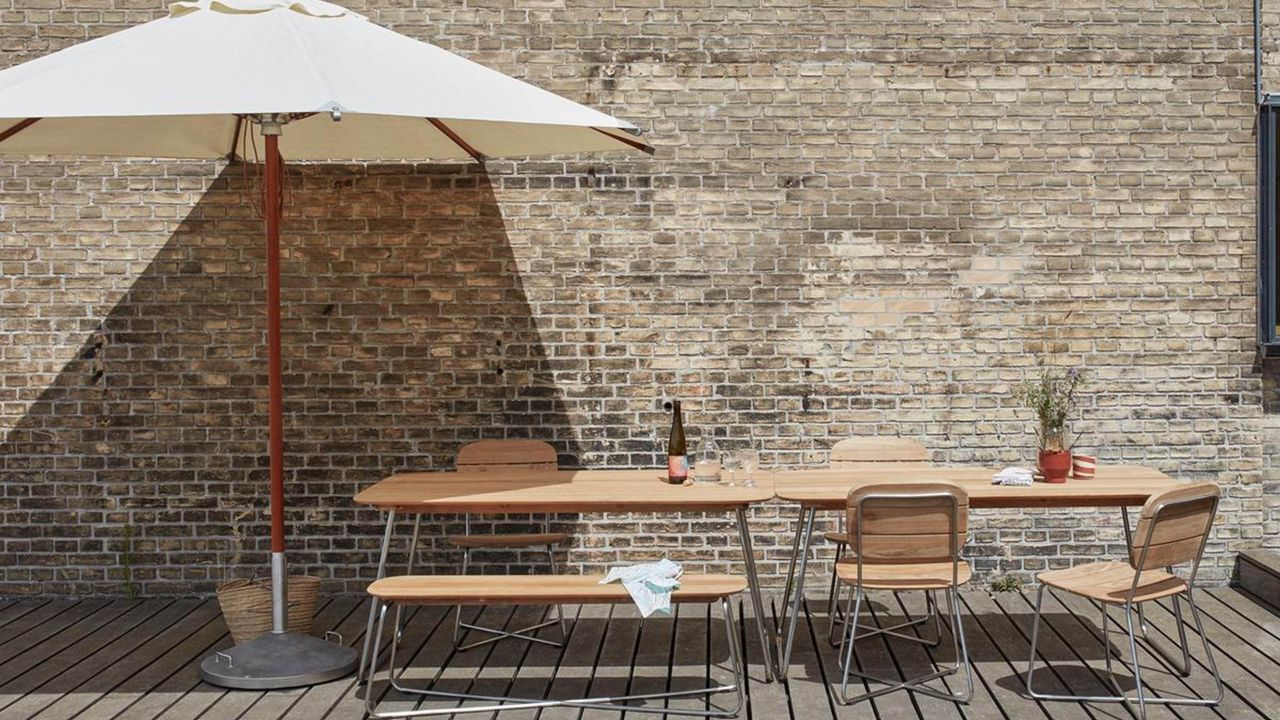 A large garden parasol over an outdoor dining table on a decked terrace