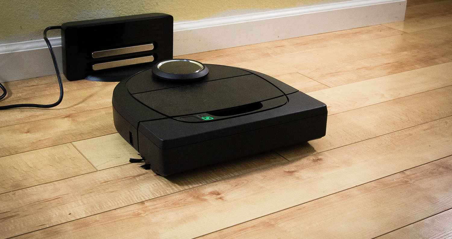 A robot vacuum cleaner charging on a hard wood floor