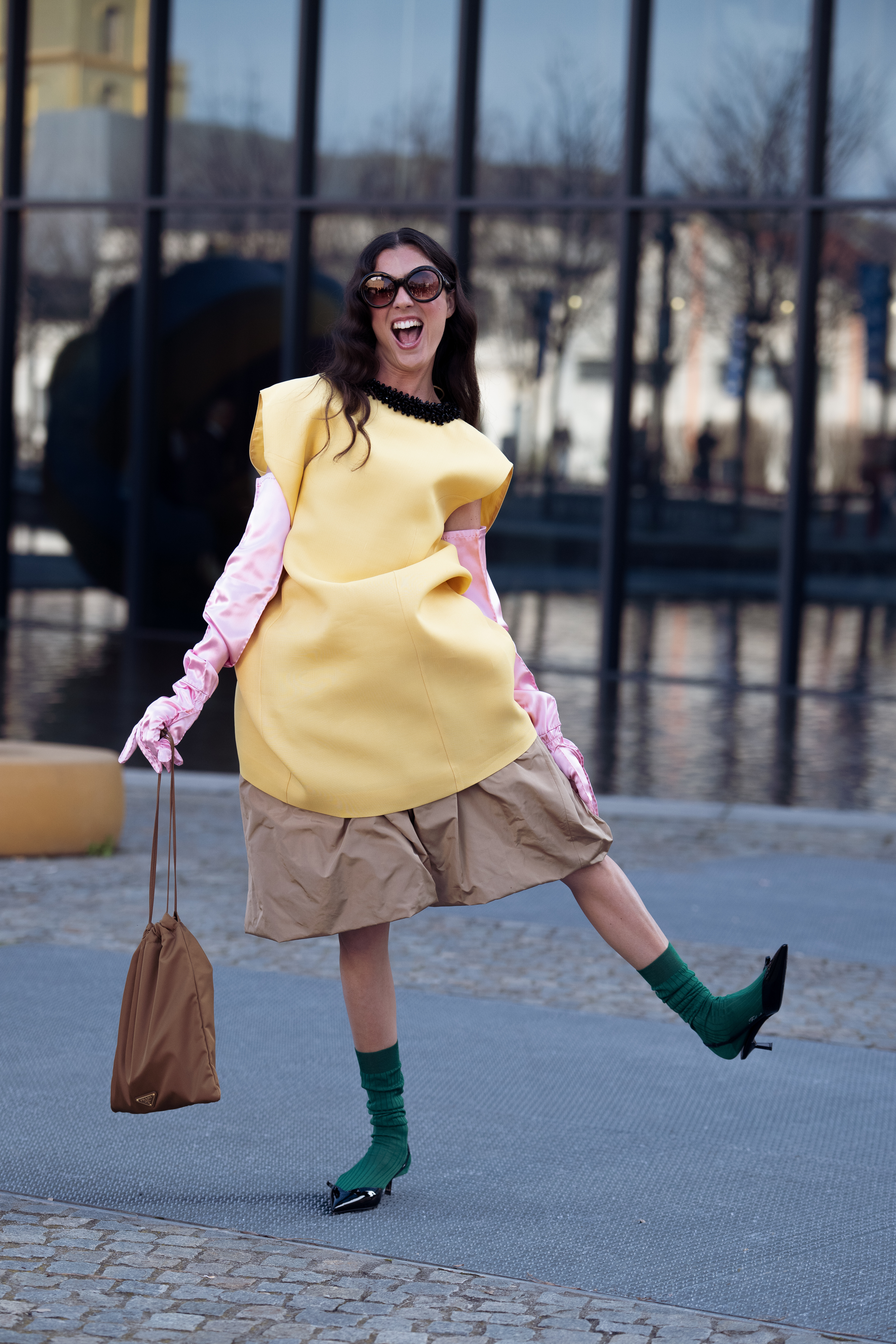 MILAN, ITALY - FEBRUARY 26: Vicki Montanari wears yellow sleeveless oversized top, pink long satin gloves, beige shorts, sunglasses, dark green socks and black pointy shoes and brown pouch Prada bag outside Prada show during the Milan Fashion Week - Womenswear Fall/Winter 2026/2027 on February 26, 2026 in Milan, Italy. (Photo by Raimonda Kulikauskiene/Getty Images)