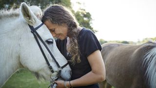 Lady resting happy head on horse