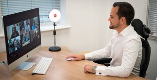 Smiling man in office using Rotolight Video Conferencing Kit, one of the best lights for Zoom calls