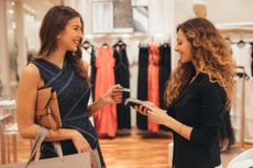 Woman paying via credit card at a clothing store.