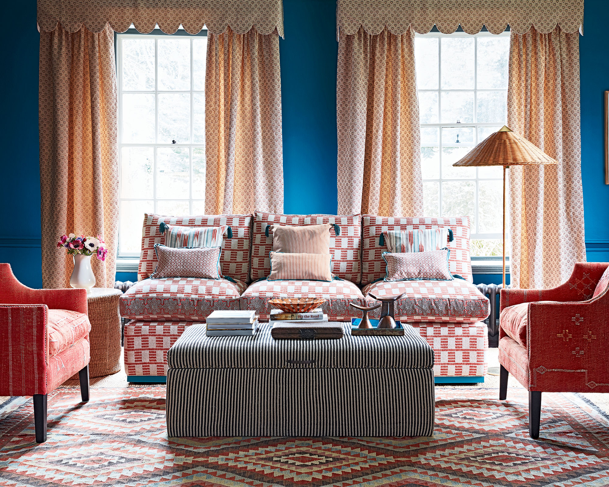 Modern living room with blue walls, patterned curtains and red accessories