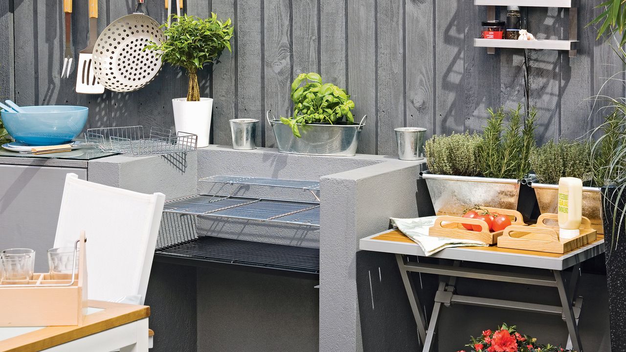 Built-in charcoal bbq with grill shelves in a grey outdoor kitchen