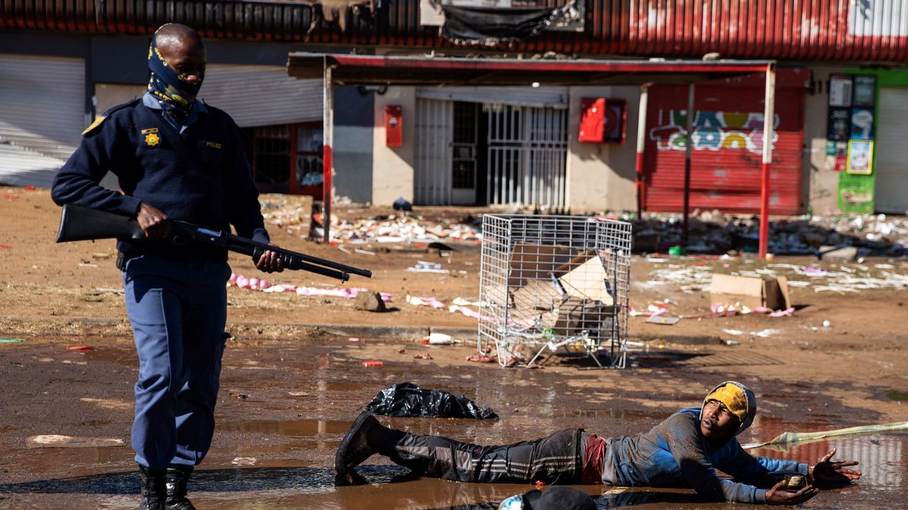 A police officer stands over a suspected looter in Soweto, Johannesburg