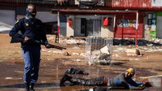 A police officer stands over a suspected looter in Soweto, Johannesburg