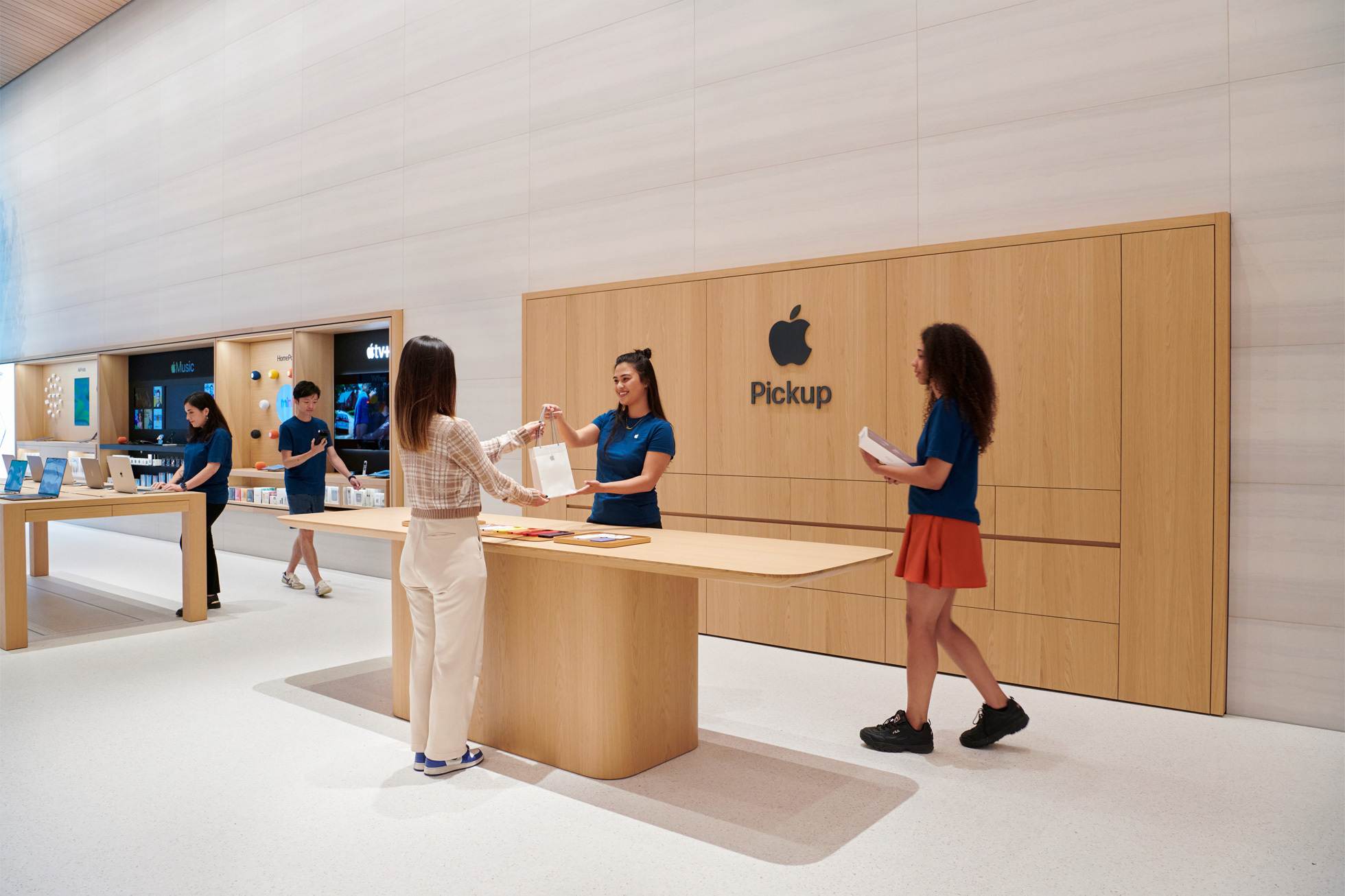 Новая зона выдачи Apple на Бромптон-роуд, где люди за столом получают новые продукты Apple