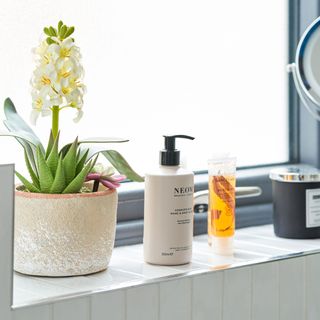 bathroom window cill with hyacinth plant and Neom hand and body lotion