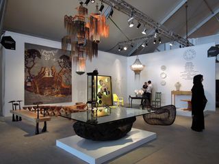 View of the Southern Guild exhibition space featuring various pieces including a table, seating, wall art and lighting