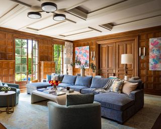 living room with wood panelled walls and large powder blue sectional sofa