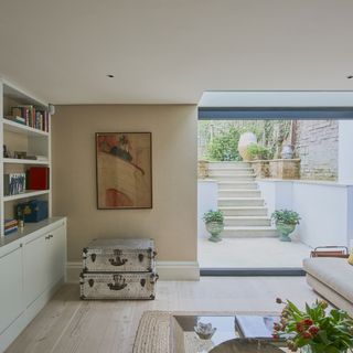 basement room with cream colour wall white shelve steps to garden and wooden flooring