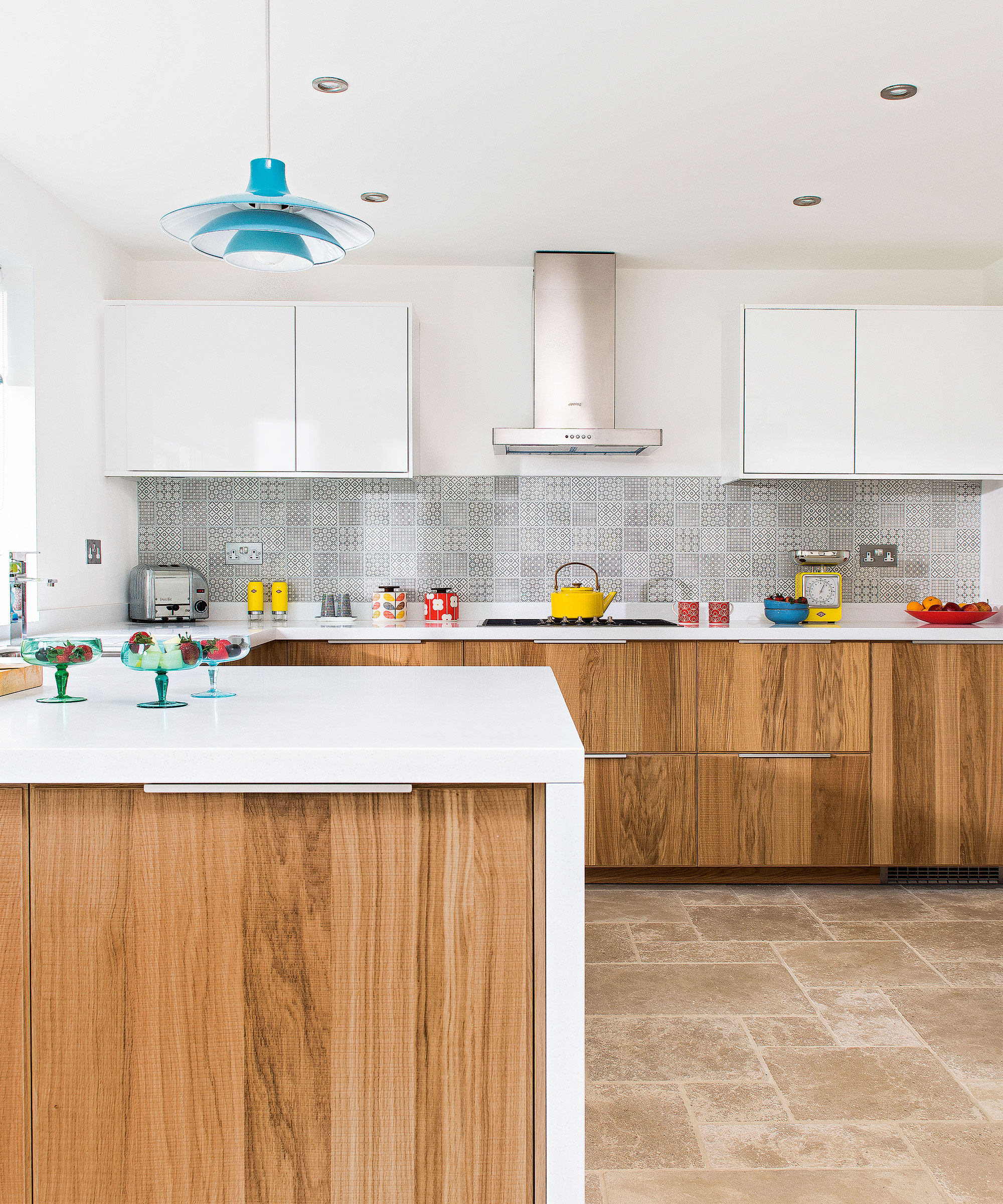 Wooden cabinets with white worktops and a blue light shade