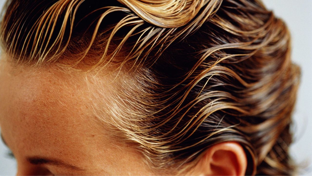 Woman with wet, combed hair, possibly while using a scalp treatment, close-up