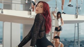Dua Lipa looking over her shoulder while walking up stairs in the Illusion music video.