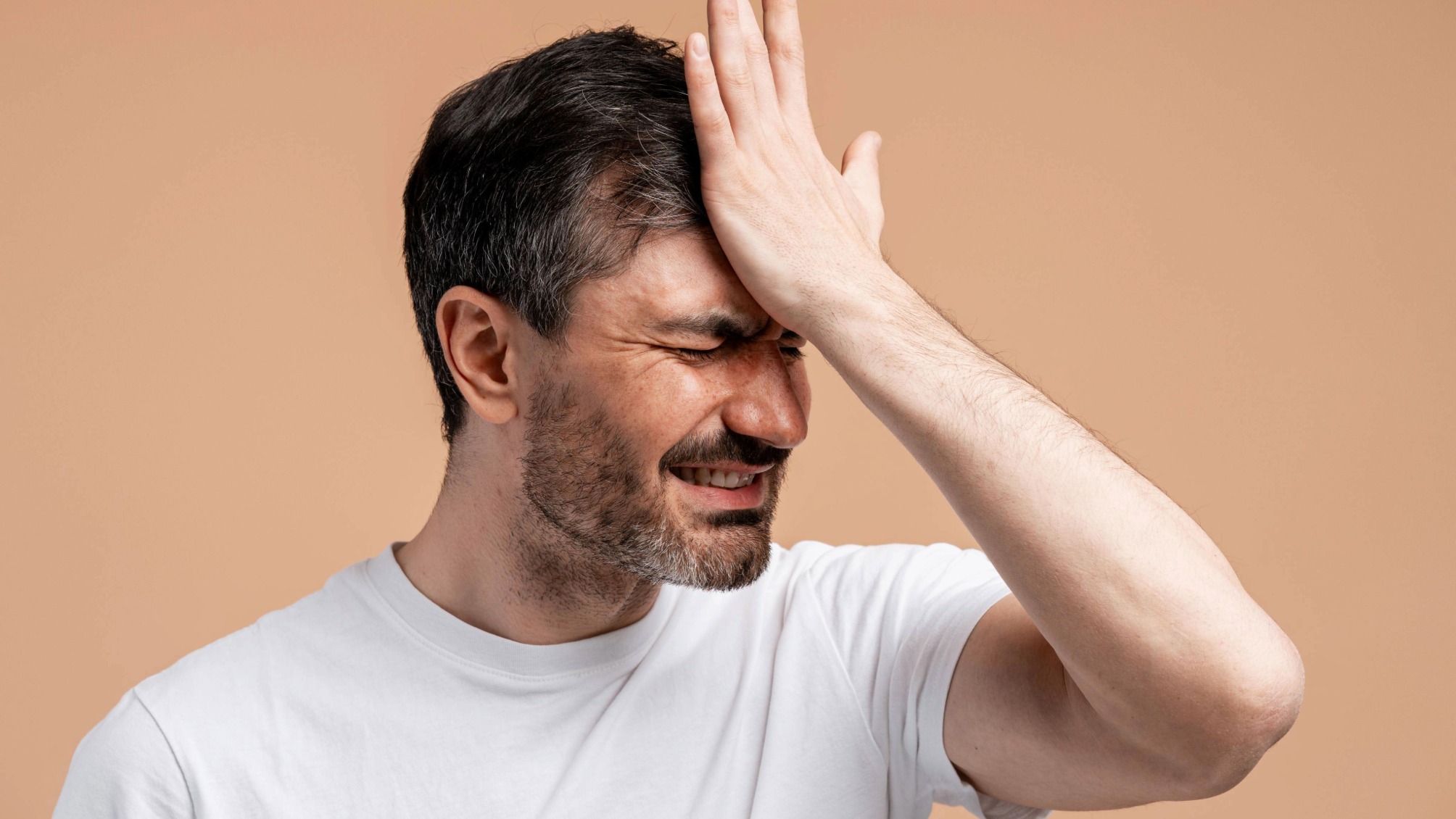 Frustrated man making facepalm showing regret and remembering a painful mistake