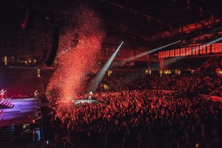 Kelsea Ballerini live in concert with red lights aglow.