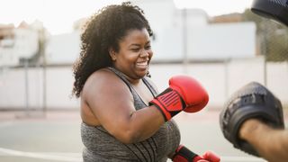 African American woman laughing while boxing outside