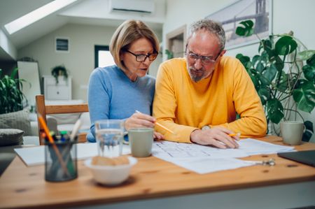 Older couple in the kitchen looking at blueprints.