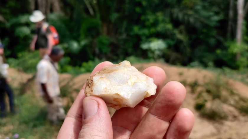 a hand holds up a rough stone tool